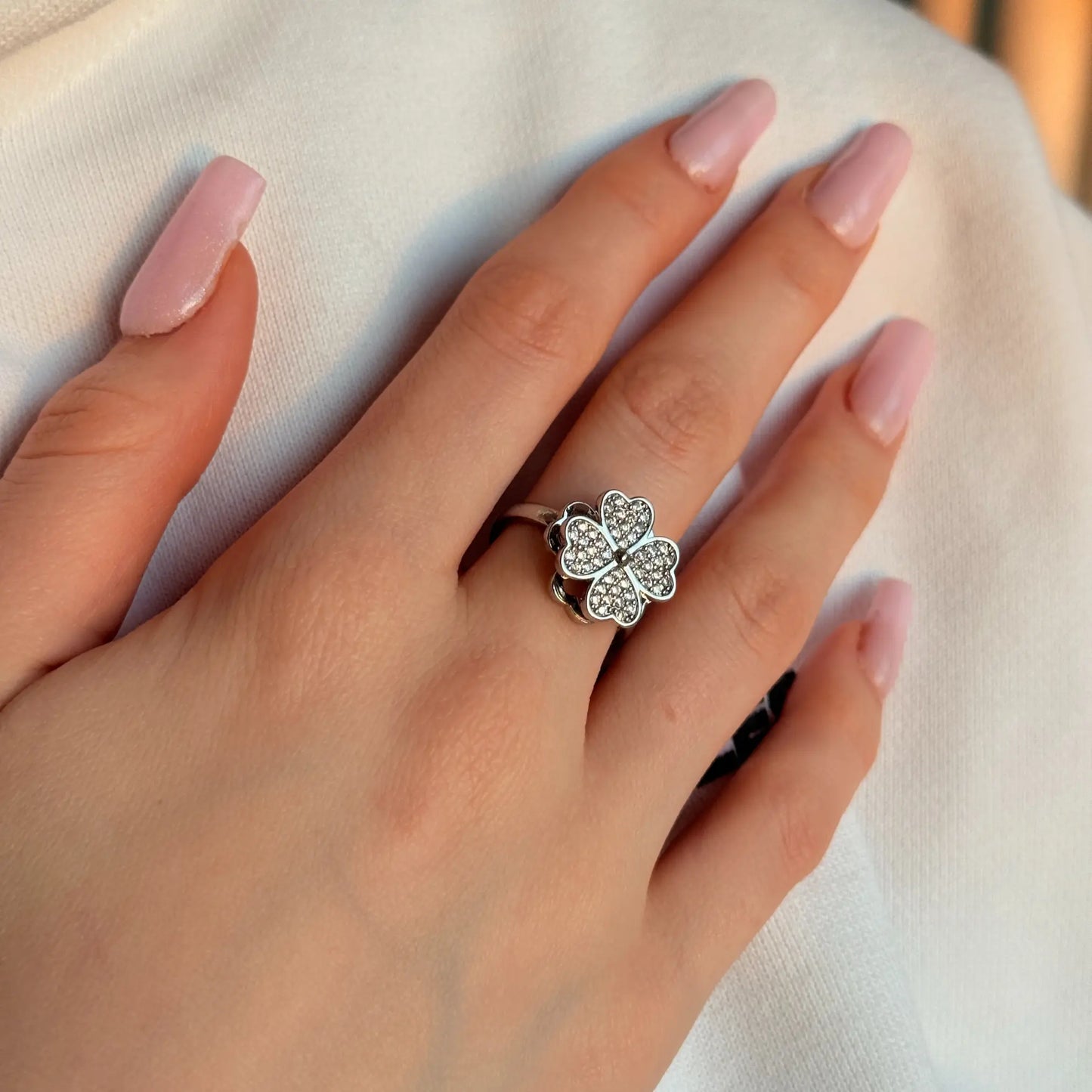 Hand wearing a silver ring with a butterfly design on a light background